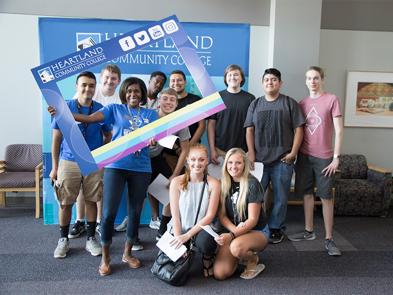 Students smiling behind a social media cutout. 