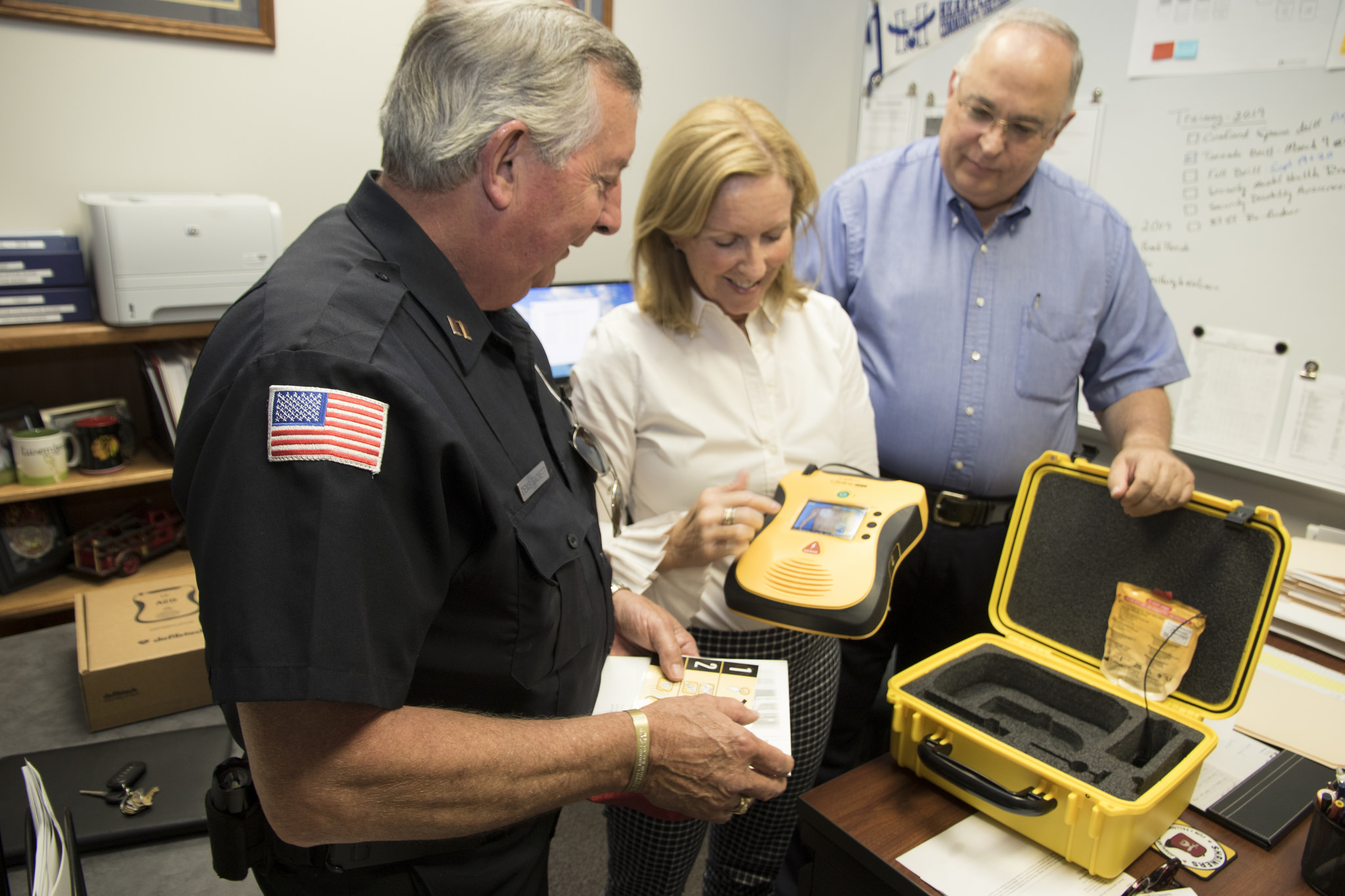 Kathi Franklin shows Denis Sackett and Keith Gehrand of HCC security services the new AED
